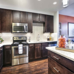 one bedroom model home kitchen with granite, tile backsplash and stainless steel appliances