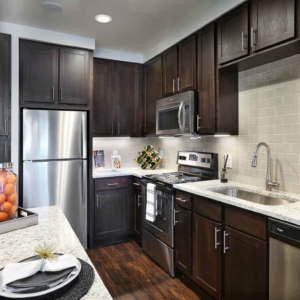 one bedroom model home kitchen with granite, tile backsplash and stainless steel appliances