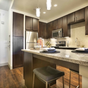 1 bedroom model home kitchen area with island bartop, granite counters and tile backsplash